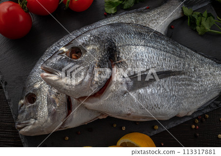 Sea bream or dorado sea fish herbs on dark slate background Top view Sea bream or dorado sea fish herbs on dark slate background Top view 113317881