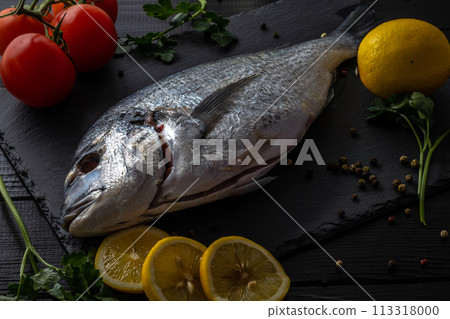 Sea bream or dorado sea fish herbs on dark slate background Top view Sea bream or dorado sea fish herbs on dark slate background Top view 113318000