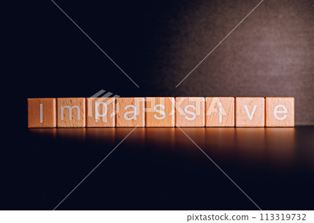 Wooden blocks form the text "Impassive" against a black background. Wooden blocks form the text "Impassive" against a black background. 113319732