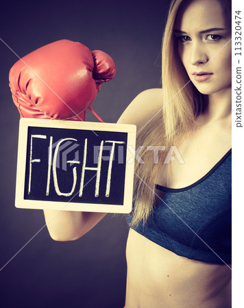 Woman wearing boxing glove holding fight sign Woman wearing boxing glove holding fight sign 113320474