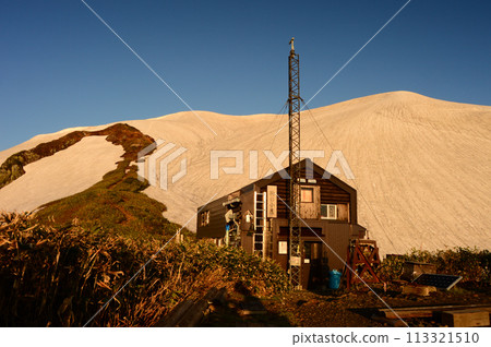 越後駒岳「駒之屋」在剩餘的雪季在早晨的陽光下閃閃發光 113321510