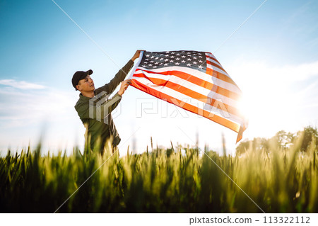 Man hold waving american USA flag. Patriot raise national american flag. Independence Day, 4th July. 113322112