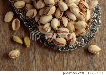 Salted pistachios on an old wooden table. Salted pistachios on an old wooden table. 113322141