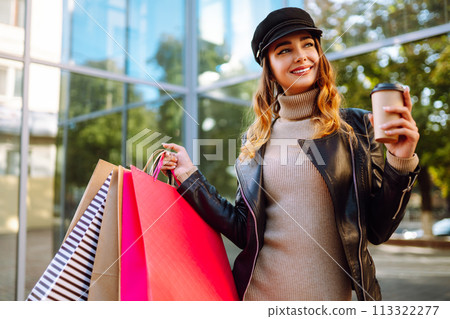 Stylish woman with shopping bags walks through the city streets. Spring Style. Stylish woman with shopping bags walks through the city streets. Spring Style. 113322277