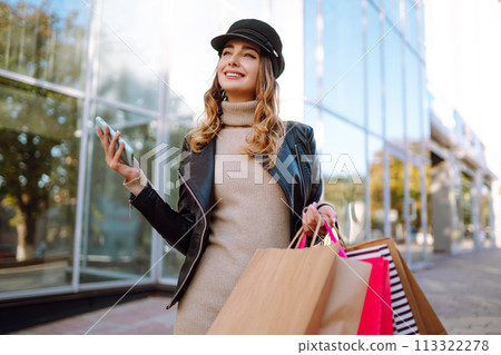 Stylish woman with shopping bags walks through the city streets. Spring Style. Stylish woman with shopping bags walks through the city streets. Spring Style. 113322278