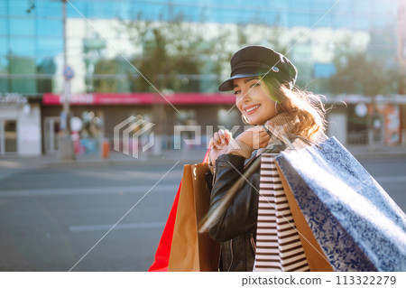 Stylish woman with shopping bags walks through the city streets. Spring Style. Stylish woman with shopping bags walks through the city streets. Spring Style. 113322279