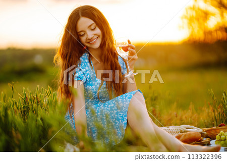 Young woman sits on a plaid with a book. Summer picnic in nature. Healthy food. Young woman sits on a plaid with a book. Summer picnic in nature. Healthy food. 113322396