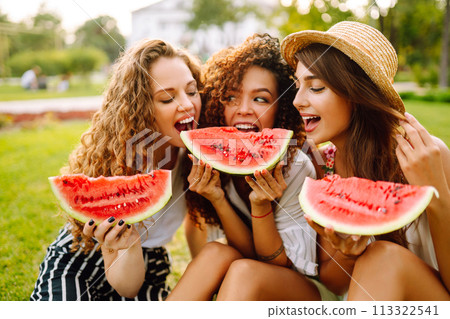 Three young woman have fun together and eating watermelon in hot summer day. 113322541