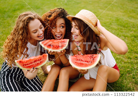Three young woman have fun together and eating watermelon in hot summer day. 113322542