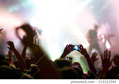 Hand with a phone records live music festival. People taking photographs with smart phone during concert. Hand with a phone records live music festival. People taking photographs with smart phone during concert. 113322594
