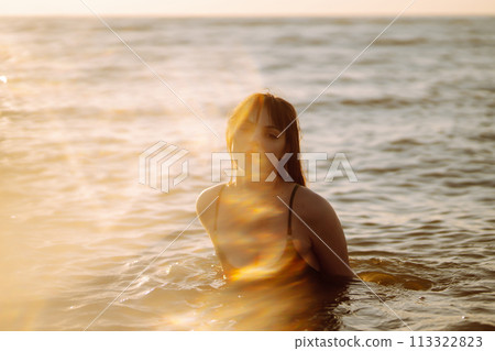 Young woman walks along seashore at sunset. Nature, relax, lifestyle concept. 113322823