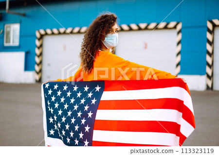 African American woman with medical face mask posing with american flag.The concept of preventing the spread of the epidemic. Covid-2019. 113323119