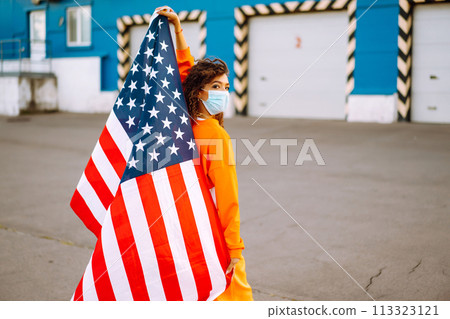 African American woman with medical face mask posing with american flag.The concept of preventing the spread of the epidemic. Covid-2019. African American woman with medical face mask posing with american flag.The concept of preventing the spread of the epidemic. Covid-2019. 113323121