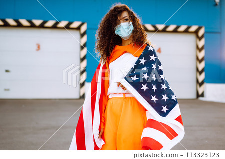 African American woman with medical face mask posing with american flag.The concept of preventing the spread of the epidemic. Covid-2019. African American woman with medical face mask posing with american flag.The concept of preventing the spread of the epidemic. Covid-2019. 113323123