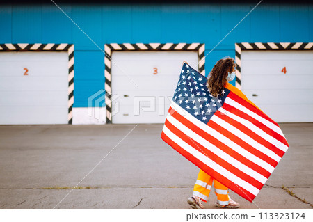 African American woman with medical face mask posing with american flag.The concept of preventing the spread of the epidemic. Covid-2019. African American woman with medical face mask posing with american flag.The concept of preventing the spread of the epidemic. Covid-2019. 113323124