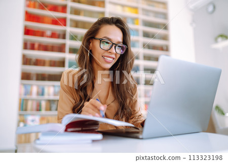 Young woman with wireless headphones calling on laptop. Online conference. Freelancer concept. 113323198