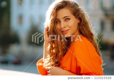 Female tourist in bright dress enjoys sights of the city on sunny day. Concept of lifestyle, fashion 113323320