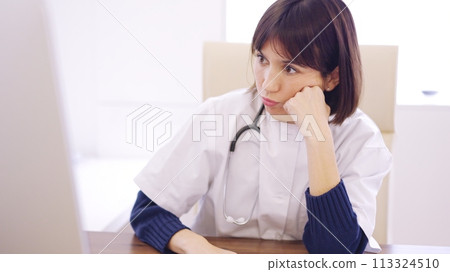 Worried female doctor looking at the screen of a computer 113324510