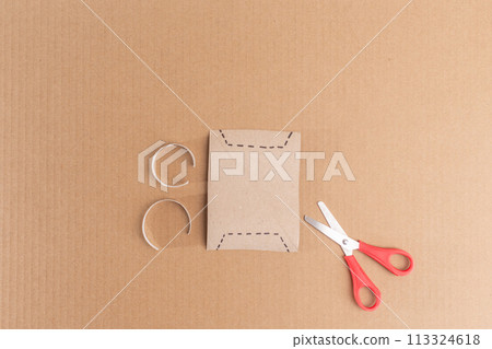 Scissors are positioned atop a cardboard-cut paper.  113324618