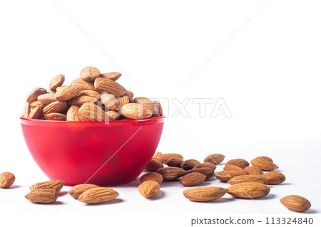 Almonds in red bowl on white background with copy space. 113324840