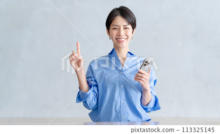 一個女人拿著智能手機和指向 113325145