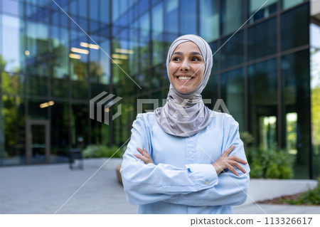 Professional Muslim woman in a hijab stands confidently outside an urban corporate building, portraying empowerment and diversity. Professional Muslim woman in a hijab stands confidently outside an urban corporate building, portraying empowerment and diversity. 113326617