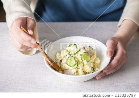 Woman's hands eating potato salad Woman's hands eating potato salad 113326787