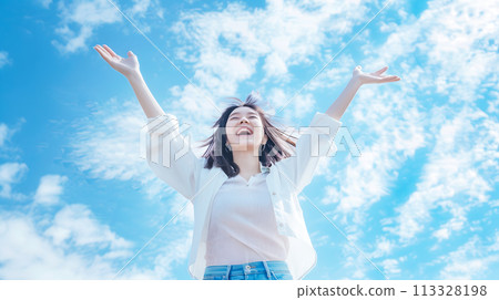 Smiling woman spreading her arms against the blue sky 113328198