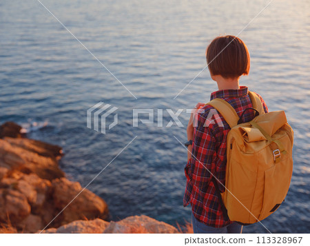 Young woman hiking on rocky beach in Spain, Benidorm. Watching the choppy sea and the bay. traveler enjoying freedom in serene nature landscape 113328967