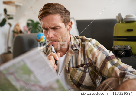 Man with serious face thinking, looking at travel map, planning vacation, going on holiday 113329584