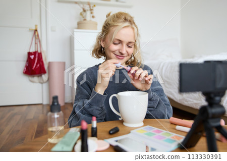 Image of happy, beautiful young social media influencer, female vlogger records a video on digital camera, tutorial on how to put makeup, getting ready for going out, talking to followers Image of happy, beautiful young social media influencer, female vlogger records a video on digital camera, tutorial on how to put makeup, getting ready for going out, talking to followers 113330391