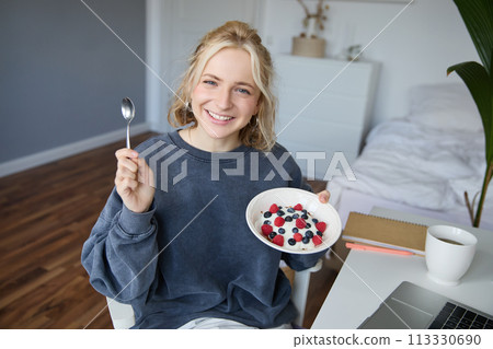 Portrait of young woman talking to audience, recording vlog on digital camera, showing her breakfast, talking about healthy food and lifestyle 113330690