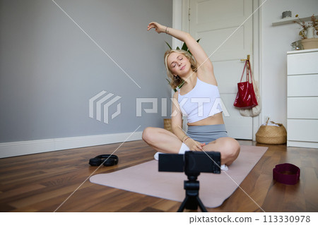 Young athletic woman trainer practicing Hatha Yoga, instructor personal training Vasisthasana, balancing pose, workout at home. Concept of healthy lifestyle and wellbeing Young athletic woman trainer practicing Hatha Yoga, instructor personal training Vasisthasana, balancing pose, workout at home. Concept of healthy lifestyle and wellbeing 113330978