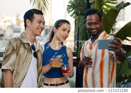 Smiling man taking selfie with best friends at party 113331280
