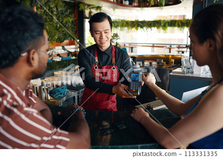 Woman paying bill for herself and her date in bar Woman paying bill for herself and her date in bar 113331335