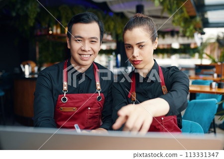 Cafe owners checking profit and expenses in report on laptop Cafe owners checking profit and expenses in report on laptop 113331347