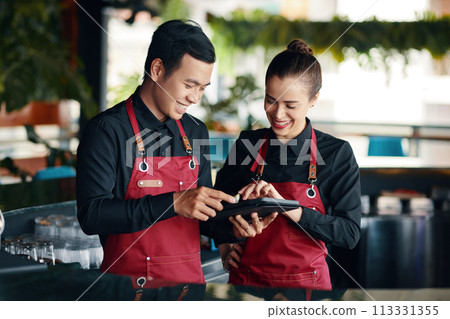 Restaurant manager teaching waiter how to use application when checking orders 113331355
