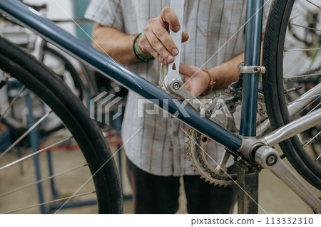Cropped shot of male mechanic working in bicycle workshop. Bike service, repair and upgrade 113332310