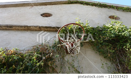 An old basketball hoop on the wall of an old country house. An old basketball hoop on the wall of an old country house. 113333423