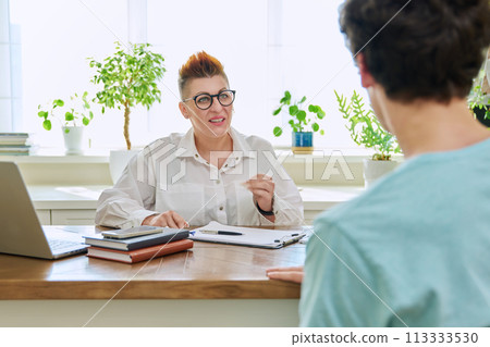 Female professional psychologist, mental therapist talking with young man in office Female professional psychologist, mental therapist talking with young man in office 113333530
