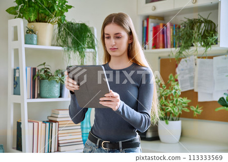 Young teenage female using digital tablet, home interior Young teenage female using digital tablet, home interior 113333569