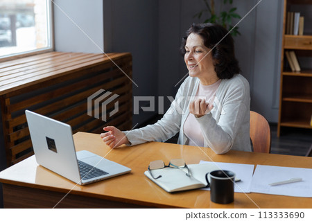 Happy middle aged senior woman sit with laptop talk on video call with friends family. Laughing mature old senior grandmother having fun talking speaking with grown up children online Happy middle aged senior woman sit with laptop talk on video call with friends family. Laughing mature old senior grandmother having fun talking speaking with grown up children online 113333690