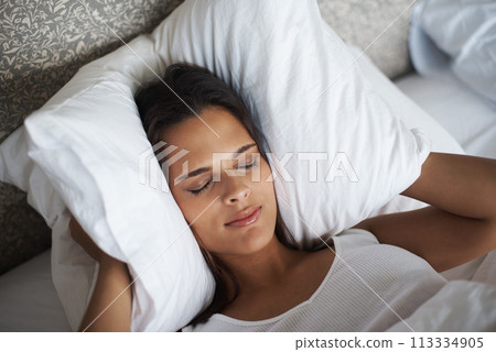Woman, pillow and frown for noise, stress or tired for insomnia or nightmare in bedroom in Las Vegas. Mental health, female person and angry for sleepless, fatigue and loud sound in hotel room 113334905