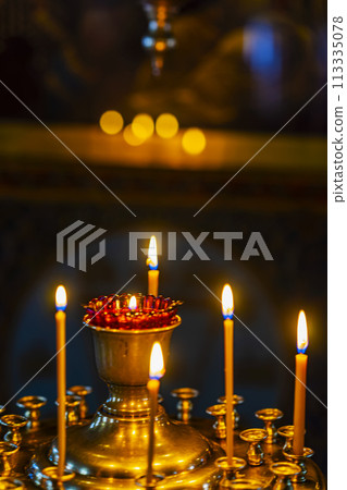Light of candles burning in gilden candlesticks in temple . Abstract background with bokeh 113335078
