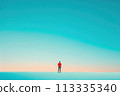 A man stands alone on a beach, looking out at the ocean 113335340