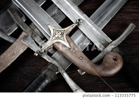 Swords and sabre on wooden background. Swords and sabre on wooden background. 113335775