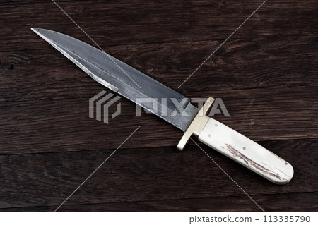 Old west bowie knife on wooden deck 113335790
