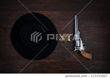Old west gun, marshal star and hat on table. Top view. Old west gun, marshal star and hat on table. Top view. 113335807