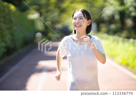 Smiling young woman running in sportswear Smiling young woman running in sportswear 113336779