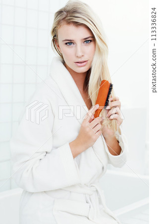 Woman, portrait and brushing hair for beauty, cosmetics or style in bathroom treatment at home. Face of young female person, girl or blonde for haircare with brush for natural grooming at house 113336824
